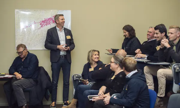 A business audience in an auditorium share a laugh with the presenter