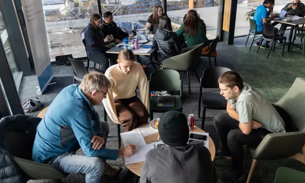 A small group have a discussion around a coffee table, taking notes